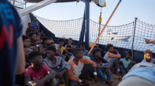 Die von der Seenotrettungsorganisation Sea-Eye herausgegebene Aufnahme zeigt Flüchtlinge an Bord des Seenotrettungsschiffs «Alan Kurdi» während ein Boot der italienischen Guardia di Finanza vorbei fährt. Foto: Fabian Heinz/Sea-eye/dpa