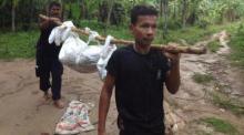 Arbeiter tragen eine der 32 gefundenen Leichen aus dem Waldstück unterhalb des Hua Sai Gebirges bei Sadao. Möglicherweise liegen dort noch weitere Tote.