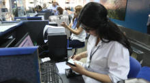 Eine Flughafenangestellte kontrolliert auf dem Internationalen Flughafen Damaskus die Tickets der Passagiere. Foto: epa/Youssef Badawi