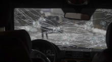 Das Glas der Windschutzscheibe eines Polizeiautos auf einer Straße ist zerbrochen und mit Einschusslöchern versehen. Foto: Vladimir Tretyakov