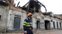 Ein Feuerwehrmann geht an einem durch ein Erdbeben beschädigten Gebäude in Petrinja, Kroatien, vorbei. Foto: epa/Antonio Bat