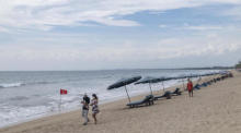 Die Touristen spazieren an einem fast leeren Strand in Kuta, Bali. Foto: epa/Made Nagi