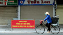 Eine Frau fährt mit dem Fahrrad an einer temporären Quarantänezone vorbei, in einer Straße in Hanoi. Foto: epa/Luong Thai Linh