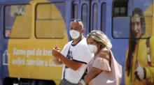 Ein Paar, das eine Gesichtsmaske trägt, geht in der kroatischen Hauptstadt Zagreb an einer Straßenbahn vorbei. Foto: epa/Antonio Bat