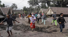 Bewohner des Dorfes Sumber Wuluh in Lumajang, Ost-Java, inspizieren ihr Dorf, das durch den Ausbruch des Mount Semeru mit Vulkanasche verschüttet wurde. Foto: epa/Ammar