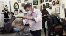 Friseur David Judge (C) trägt eine Gesichtsmaske, während er dem Kunden Robert Redmond (L) im Abner Browns Barbershop im Dubliner Vorort Rathmines einen Haarschnitt verpasst. Foto: epa/Bryan Meade