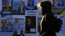 Eine Frau aus Rumänien, die eine Schutzmaske trägt, geht neben einem Wahlkampfkomitee für Parlamentswahlen vorbei. Foto: epa/Robert Ghement