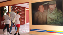 Eine Gruppe kubanischer Ärzte geht neben einem Wandgemälde mit den Bildern der ehemaligen Präsidenten Fidel Castro und Hugo Chávez. Foto: Guillermo Nova/Dpa