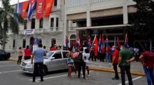 Einige Personen mit kubanischen Fahnen stehen vor dem nationalen Hauptquartier der Union der Jungen Kommunisten (UJC) in Havanna. Foto: epa/Ernesto Mastrascusa