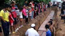 Schaulustige, darunter auch Kinder benachbarter Dörfer, beobachten die Bergung der 26 Leichen bei Pedang Basar. Mittlerweile werden bis zu 500 Opfer befürchtet.