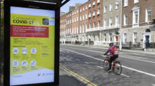 Eine Radfahrerin fährt an einer Bushaltestelle mit einer Gesundheitswarnung auf der Covid-19 in Dublin vorbei. Foto: epa/Aidan Crawley