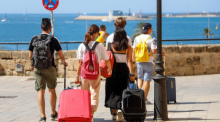 Touristen gehen mit ihren Rollkoffern durch die Stadt. Angesichts steigender Corona-Zahlen geht auch auf Mallorca und den anderen Balearen-Inseln die Angst um, zu einem Corona-Risikogebiet erklärt zu werden. Foto: Clara Margais/dpa