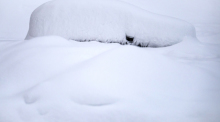 St. Moritz: Ein Auto ist nach starkem Schneefall vollständig von Schnee bedeckt. Foto: Jean-Christophe Bott/Keystone/dpa