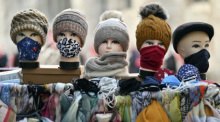 Schaufensterpuppen-Köpfe mit Gesichtsmasken, Tüchern und Mützen stehen vor einem Bekleidungsgeschäft in der Altstadt. Foto: Martin Schutt/dpa-zentralbild/dpa