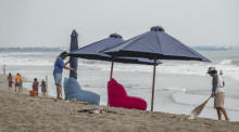 Arbeiter stellen Sonnenschirme an einem Strand in Canggu, Bali, auf. Foto: epa/Made Nagi