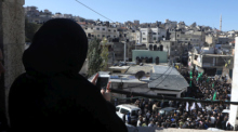 Palästinensische Frau beobachtet trauernde Menschen in Ramallah. Foto: epa/Alaa Badarneh