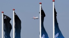Bei der Landung eines Flugzeugs auf dem Flughafen Schönefeld wehen Fahnen mit dem ILA-Logo im Wind. Archivfoto: epa/RALF HIRSCHBERGER