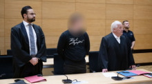 Der Angeklagte steht im Landgericht zwischen seinen Anwälten Ali Mojab (l) und Martin Lindemann. Der 20-Jährige soll bei einer Polizeikontrolle Gas gegeben und zwei Polizisten angefahren haben. Foto: Bernd Thissen/dpa