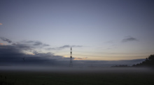 Ein Strommast ist auf einem Feld vom Morgennebel umgeben. Foto: Frank Molter/dpa