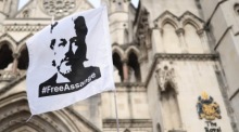 Julian Assange flattert mit einer Flagge, als Unterstützer vor dem Royal Courts of Justice in London protestieren. Foto: epa/Neil Hall