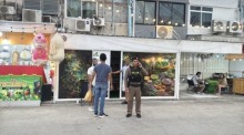 Ein Polizeibeamter und die Geschädigten stehen vor dem Geschäft, in dem die umstrittenen Kräuterprodukte verkauft worden sein sollen. Bild: TMN.TV