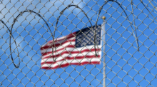Eine US-Flagge weht hinter Stacheldraht auf dem Marinestützpunkt Guantánamo Bay auf Kuba. Hier betreiben die USA seit mehr als 21 Jahren ein umstrittenes Gefangenenlager. Foto: Magdalena Miriam Tröndle/dpa