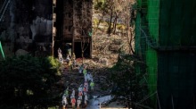 Feuerwehrleute und Mitarbeiter der Disaster Victim Identification (DVI)-Einheit verlassen einen vom Feuer zerstörten Turm im Wohnviertel Wang Fuk Court in Hongkong. Foto: epa/Leung Man Hei