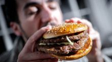 Ein Mann beißt in einen Burger. Foto: Sina Schuldt/dpa