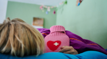 Ein Kind liegt mit Wärmflasche im Bett. Foto: Annette Riedl/dpa