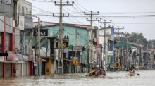 Menschen waten nach heftigen Regenfällen durch eine überflutete Straße bei Colombo, zahlreiche Regionen stehen weiter unter Wasser. Foto: EPA/Chamila Karunarathne