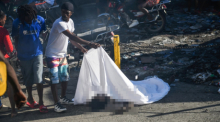 In einer Straße in Port-au-Prince deckt ein Mann den Körper einer Person auf dem Boden zu. Foto: epa/Johnson Sabin