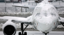 Ein verschneites Flugzeug steht am Flughafen. Die Sperrung des Flugbetriebes am Münchner Flughafen ist wegen starker Schneefälle bis 03.12.2023 um 6.00 Uhr verlängert worden. Foto: Karl-Josef Hildenbrand/dpa