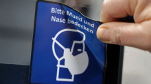 In der Werkstatt der Rostocker Straßenbahn AG RSAG wird an einer Straßenbahn-Tür ein Piktogramm mit dem Hinweis auf die Maskenpflicht entfernt. Foto: Bernd Wüstneck/dpa