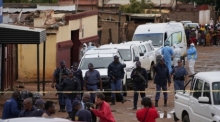 Schaulustige versammeln sich am Ort des Vorfalls, bei dem Bewaffnete in einer Kneipe in Bekkersdal mindestens neun Menschen töteten und mindestens zehn verletzten. Foto: Alfonso Nqunjana/Ap/dpa