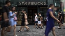 Chinesische Menschen gehen an einer Filiale der amerikanischen Kaffeekette Starbucks in Peking vorbei. Foto: epa/Roman Pilipey