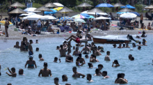 Menschen genießen das Meer im Vorort Glyfada in Athen. Griechenland befindet sich auf dem Höhepunkt der aktuellen Hitzewelle - die Wetterstationen im Land verzeichneten bereits am Freitag Werte über 40 Grad. Foto: Yorgos Karahalis/Ap/dpag