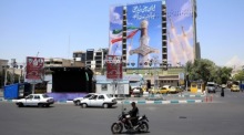 Autofahrer passieren auf dem Vanak-Platz in Teheran ein riesiges Propagandaplakat mit Raketenmotiven während der Spannungen zwischen Iran und den USA. Foto: Abedin Taherkenareh/epa/dpa