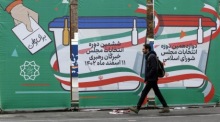 Ein Mann geht in einer Straße in Teheran neben dem Wahlplakat für die bevorstehenden Parlamentswahlen spazieren. Foto: epa/Abedin Taherkenareh
