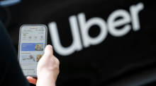 Ein Nutzer öffnet die Uber-App vor einem Mietwagen des Fahrdienstvermittlers in Berlin. Foto: Sebastian Gollnow/dpa