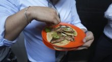 Ein Kunde drückt Limettensaft auf seine Tacos am Stand von Tacos El Califa de León. Tacos El Califa de León ist der erste Taco-Stand überhaupt, der einen Michelin-Stern des französischen Restaurantführers erhalten h... Foto: Fernando Llano/Ap/dpa