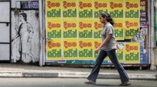Eine sri-lankische Frau geht an Wahlplakaten der Kandidaten für die bevorstehenden Präsidentschaftswahlen in Colombo vorbei. Foto: epa/Chamila Karunarathne