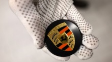 Ein Mitarbeiter hält in der Porsche Exclusive Manufaktur in Stuttgart eine Radnabenabdeckung für einen Porsche-Sportwagen. Foto: epa/Anna Szilagyi