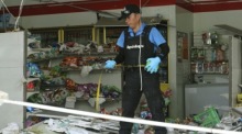 Ein thailändischer Polizeibeamter inspiziert den Ort der Bombenexplosion in einem Lebensmittelgeschäft in Pattani. Foto: EPA/Abdullah Wangni