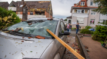 Eine Dachlatte steckt in der Windschutzscheibe eines parkenden Autos. Ein Unwetter hat auch in Paderborn große Schäden angerichtet. Foto: Lino Mirgeler/dpa