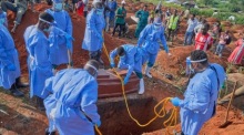 Mitarbeiter lassen bei einer Beisetzung in Bunia den Sarg eines Ebola-Opfers in ein Grab hinab. Foto: EPA/Dieudonne Dirole