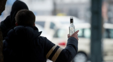 Ein stark alkoholisierter Mann gestikuliert am Hauptbahnhof in Hamburg mit einer Wodkaflasche in der Hand. Foto: Daniel Reinhardt/dpa