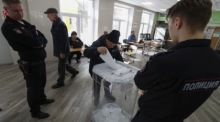 Russische Polizisten bewachen eine Wahlurne, während ein älterer Mann während der Präsidentschaftswahlen in Moskau seine Stimme abgibt. Foto: EPA-EFE/Maxim Shipenkov