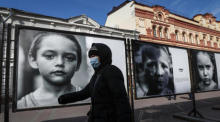 Eine Frau geht an Fotos vorbei, die im Rahmen der Ausstellung "Blick in die Augen des Donbass" in Moskau ausgestellt sind. Foto: epa/Yuri Kochetkov