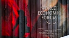 Das Logo des WEF und die Reflexion einer KI-generierten Projektion sind abgebildet, während eine Frau am Schlusstag des 54. Jahrestreffens des Weltwirtschaftsforums (WEF) in Davos vorbeigeht. Foto: epa/Gian Ehrenzeller