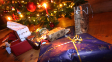 Verpackte Geschenke liegen in einem Wohnzimmer unter einem festlich geschmücktem Weihnachtsbaum. Foto: Karl-Josef Hildenbrand/dpa